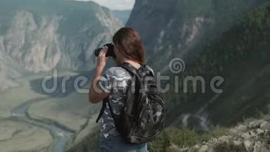 女旅行者<strong>站在山顶</strong>时，用相机拍摄美丽的照片。